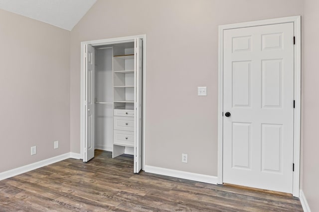 unfurnished bedroom featuring dark hardwood / wood-style floors and lofted ceiling