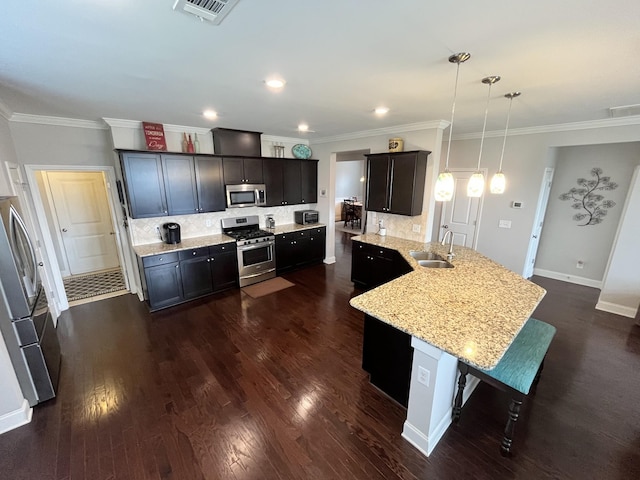 kitchen with a kitchen breakfast bar, sink, tasteful backsplash, decorative light fixtures, and stainless steel appliances