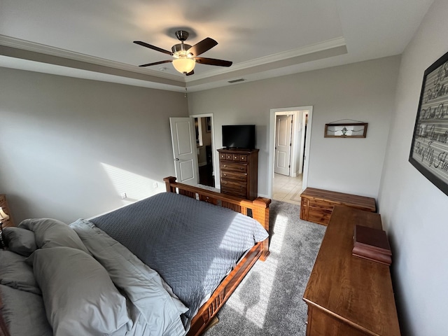 carpeted bedroom featuring a raised ceiling, ceiling fan, and crown molding