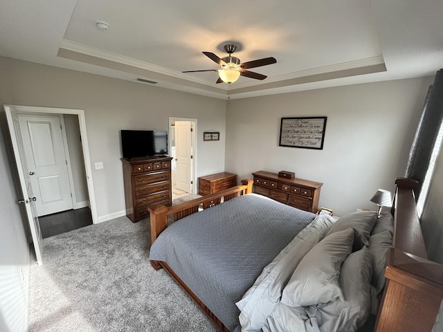 bedroom with dark colored carpet, a raised ceiling, and ceiling fan