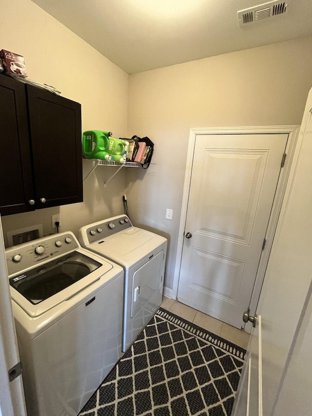 laundry room featuring cabinets, washing machine and dryer, and tile patterned flooring