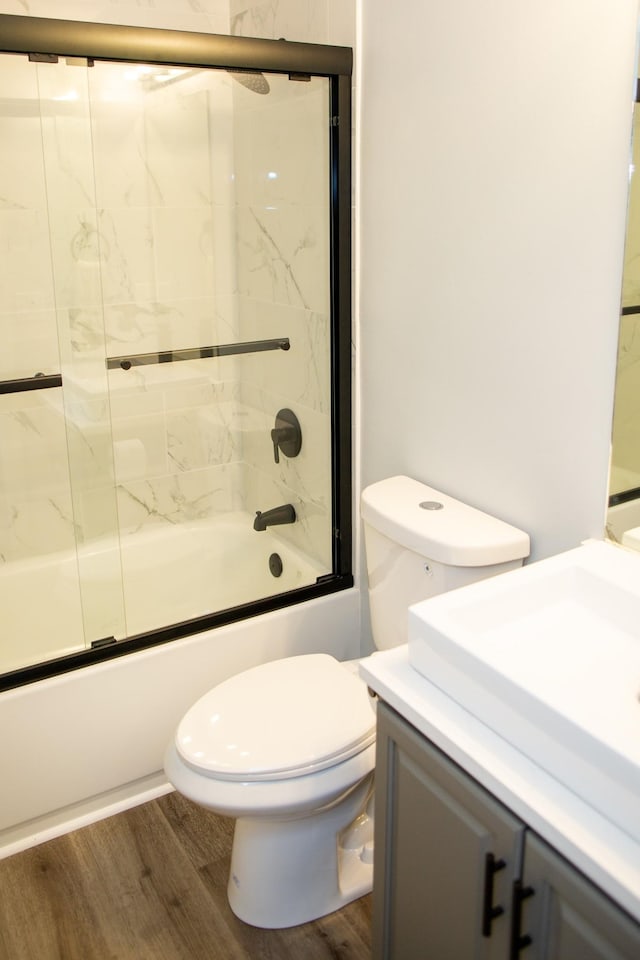 full bathroom featuring toilet, wood-type flooring, shower / bath combination with glass door, and vanity