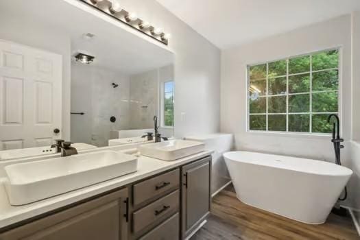 bathroom with wood-type flooring, separate shower and tub, plenty of natural light, and vanity