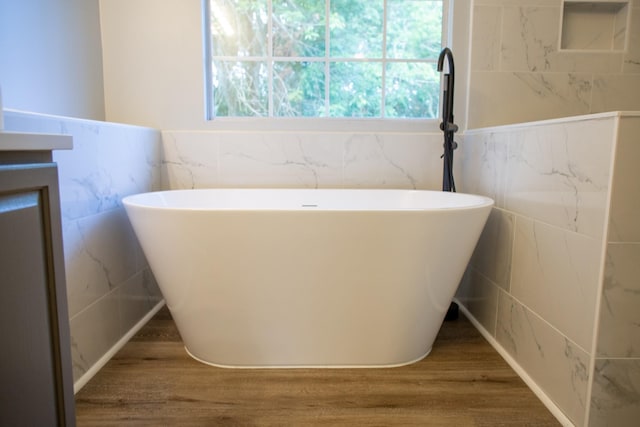 bathroom with vanity, hardwood / wood-style floors, a bathtub, and tile walls