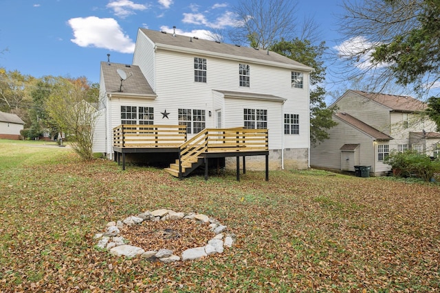 back of property with a lawn, a deck, and an outdoor fire pit