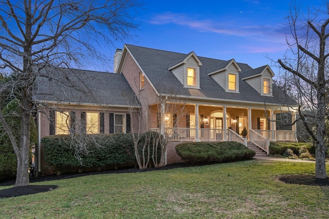 cape cod-style house featuring a porch and a lawn