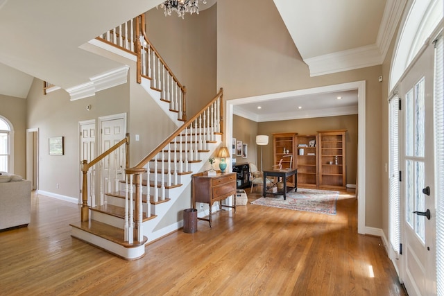 foyer entrance with crown molding, light hardwood / wood-style floors, a healthy amount of sunlight, and a high ceiling