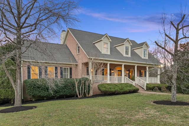 new england style home featuring a yard and a porch