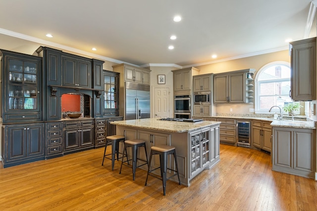 kitchen with wine cooler, a kitchen bar, a center island, built in appliances, and light hardwood / wood-style floors