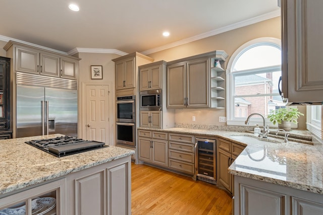 kitchen with sink, beverage cooler, ornamental molding, built in appliances, and light stone countertops