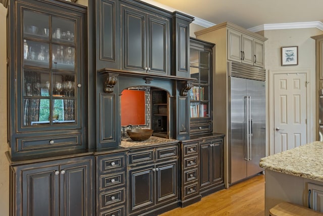 kitchen featuring ornamental molding, appliances with stainless steel finishes, light stone countertops, and light wood-type flooring