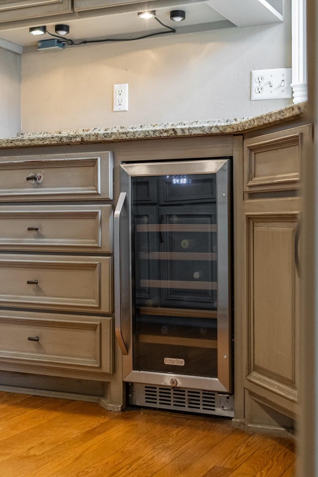 interior details with beverage cooler, light stone countertops, and light hardwood / wood-style flooring