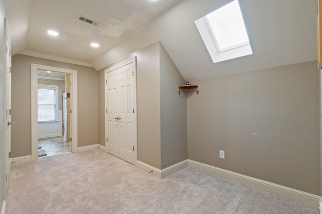 corridor featuring lofted ceiling with skylight and light colored carpet