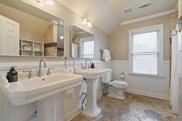 bathroom featuring lofted ceiling, crown molding, toilet, and dual sinks