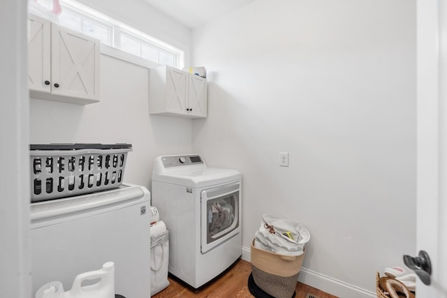 washroom with washer and clothes dryer, cabinets, and light hardwood / wood-style flooring