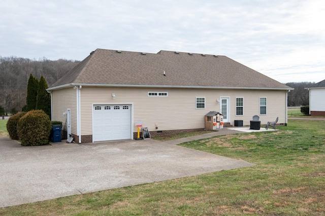 back of property featuring a garage, a yard, and a patio