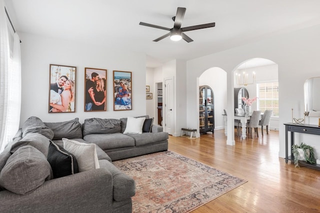 living room with ceiling fan with notable chandelier and light wood-type flooring