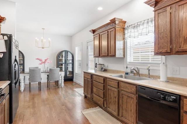 kitchen with sink, hanging light fixtures, black dishwasher, refrigerator with ice dispenser, and a chandelier