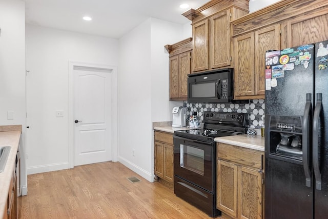 kitchen with black appliances, light hardwood / wood-style floors, and backsplash