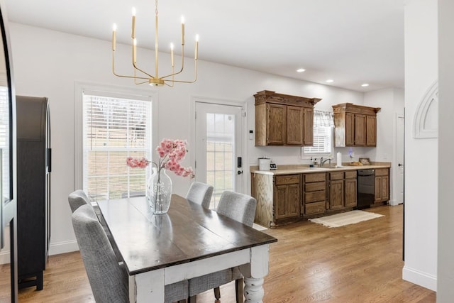 dining space featuring light hardwood / wood-style flooring, a notable chandelier, a healthy amount of sunlight, and sink