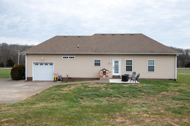 rear view of house with a garage, a patio area, and a yard