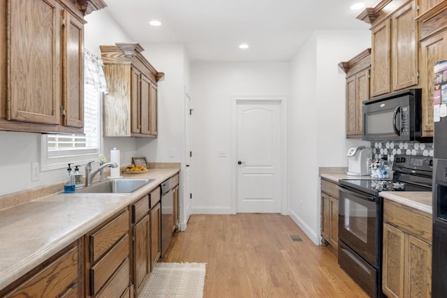 kitchen featuring black appliances, decorative backsplash, light wood-type flooring, and sink