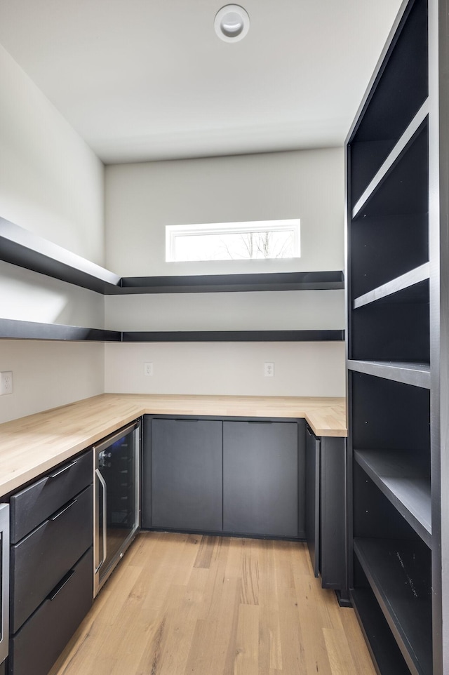 kitchen with wine cooler, light hardwood / wood-style flooring, and wooden counters