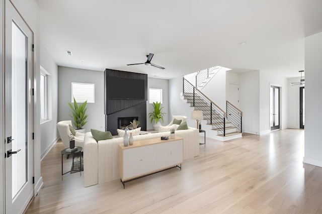 living room featuring ceiling fan, a fireplace, and light hardwood / wood-style flooring