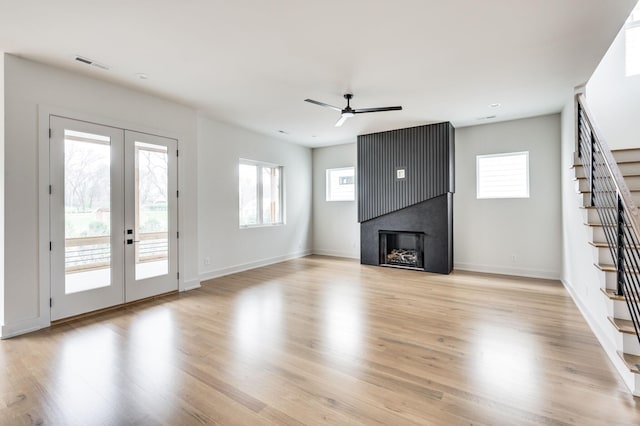 unfurnished living room with ceiling fan, french doors, and light hardwood / wood-style floors