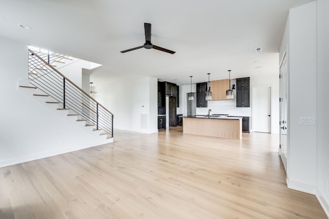 unfurnished living room featuring ceiling fan, sink, and light hardwood / wood-style flooring