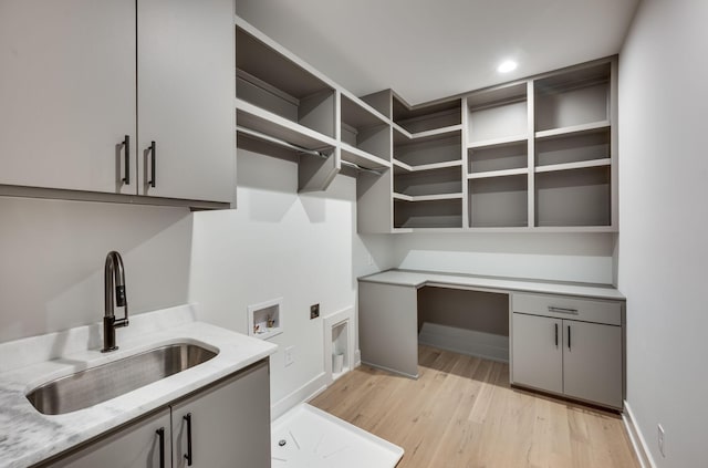 clothes washing area featuring electric dryer hookup, cabinets, sink, light hardwood / wood-style flooring, and washer hookup