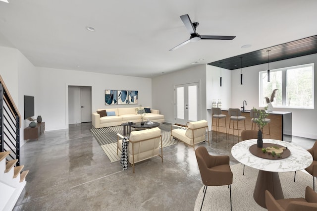 living room featuring concrete flooring, french doors, and ceiling fan