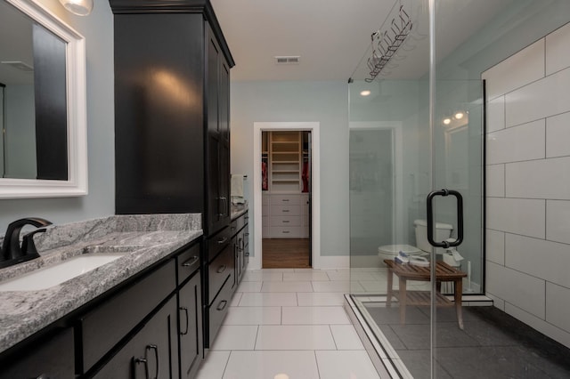 bathroom featuring tile patterned flooring, vanity, toilet, and walk in shower