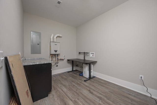 misc room with light wood-type flooring, electric panel, and tankless water heater