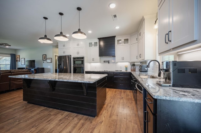 kitchen with sink, decorative light fixtures, a kitchen island, wood-type flooring, and stainless steel appliances