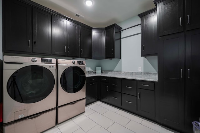 washroom with washer and clothes dryer, cabinets, and light tile patterned floors