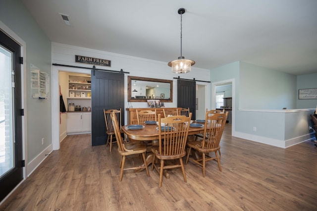 dining room with a barn door, a wealth of natural light, and hardwood / wood-style floors