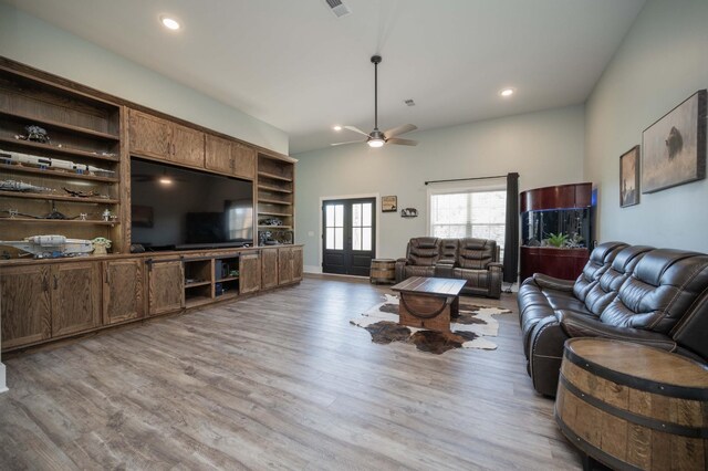 living room featuring french doors, light wood-type flooring, ceiling fan, and built in shelves