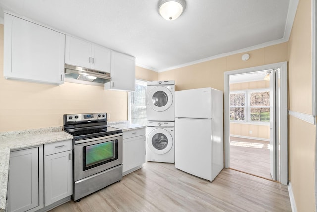 kitchen featuring light hardwood / wood-style flooring, stacked washer and clothes dryer, white fridge, stainless steel electric range oven, and plenty of natural light