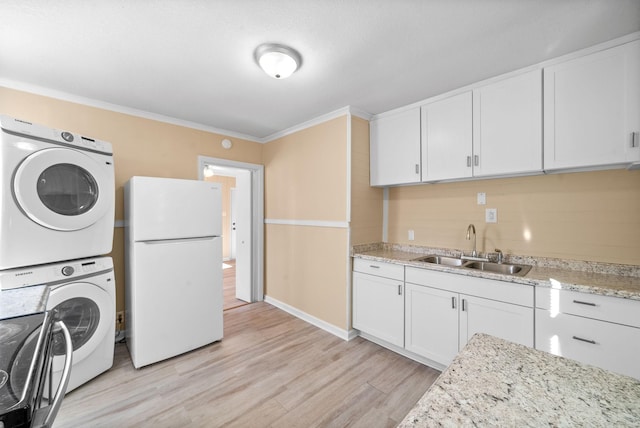 clothes washing area featuring stacked washer / drying machine, light wood-type flooring, sink, and ornamental molding