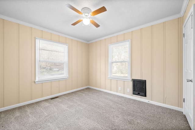 carpeted empty room with ceiling fan, crown molding, and heating unit