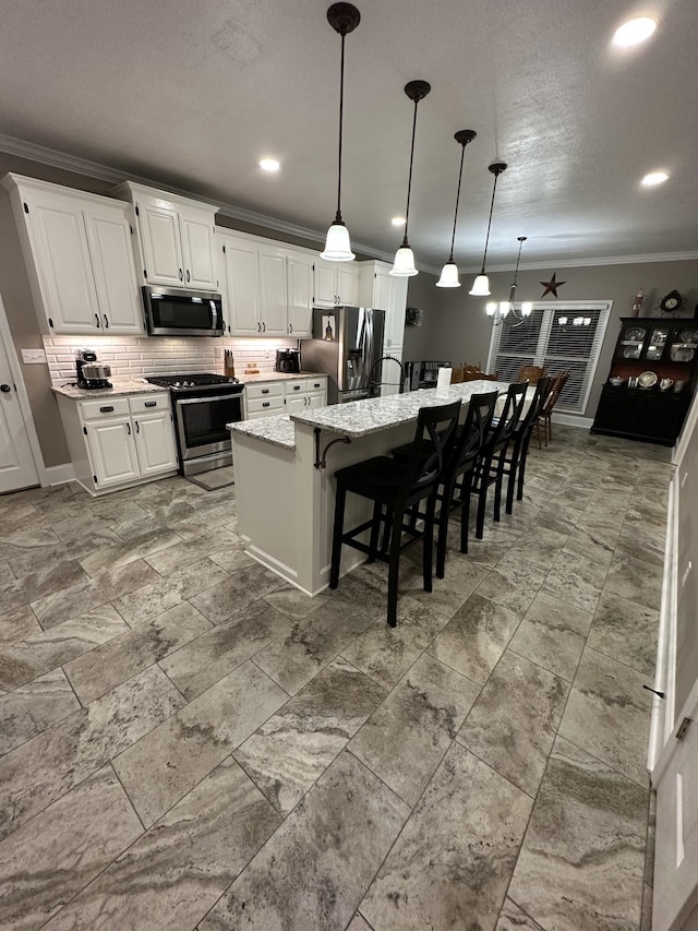 kitchen featuring ceiling fan, a kitchen island, light stone counters, white cabinetry, and stainless steel appliances