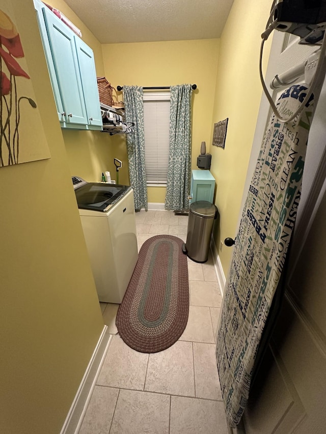 laundry room featuring cabinets, light tile patterned flooring, washer / dryer, and a textured ceiling