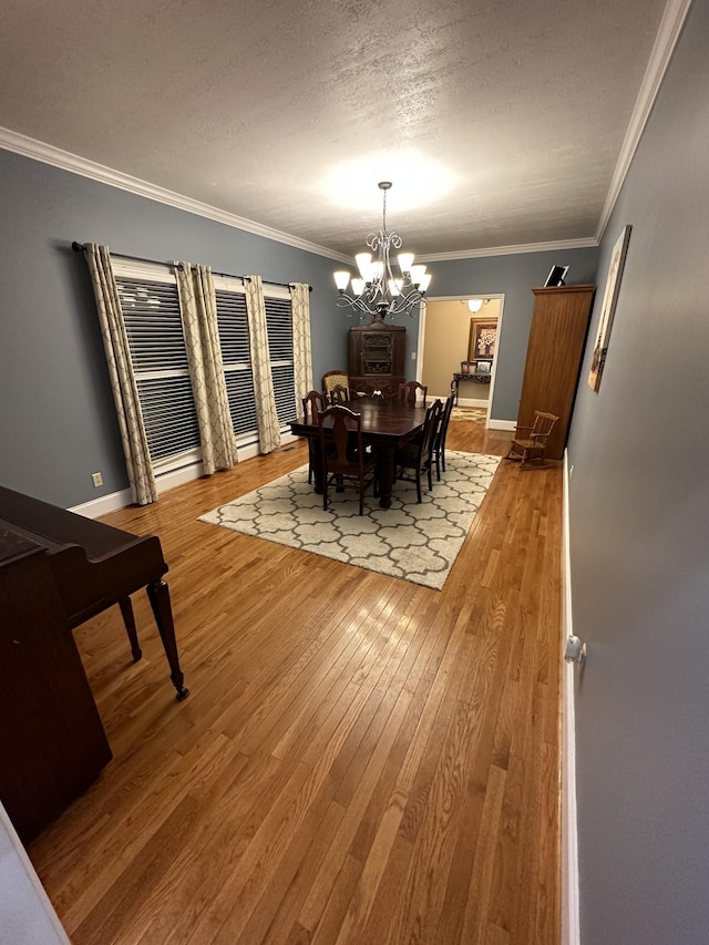 dining area featuring crown molding, hardwood / wood-style floors, a textured ceiling, and a notable chandelier