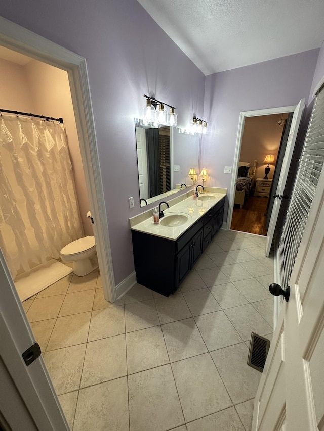 bathroom featuring tile patterned floors, vanity, toilet, and a textured ceiling