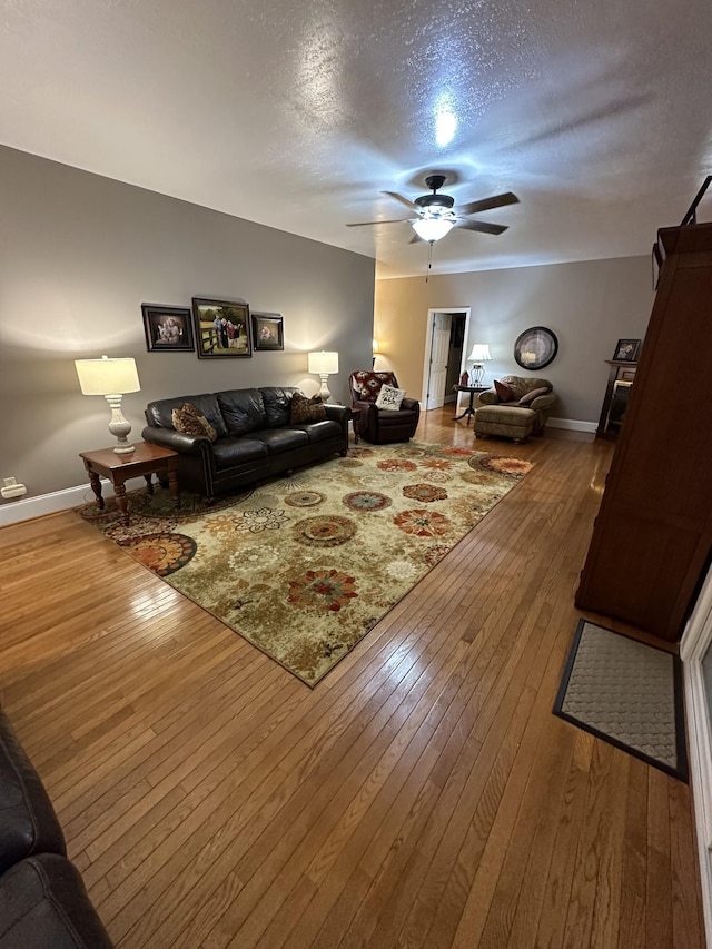 living room featuring ceiling fan, wood-type flooring, and a textured ceiling