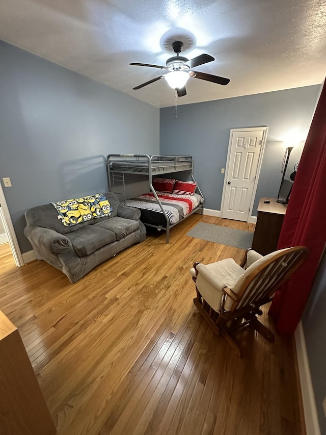 bedroom featuring ceiling fan, hardwood / wood-style floors, and a textured ceiling