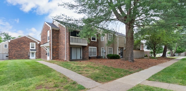 view of front of house featuring a balcony and a front yard