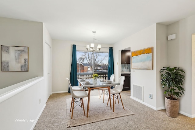 carpeted dining area featuring a chandelier