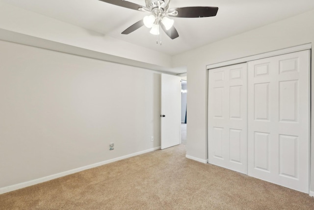 unfurnished bedroom with ceiling fan, light colored carpet, and a closet